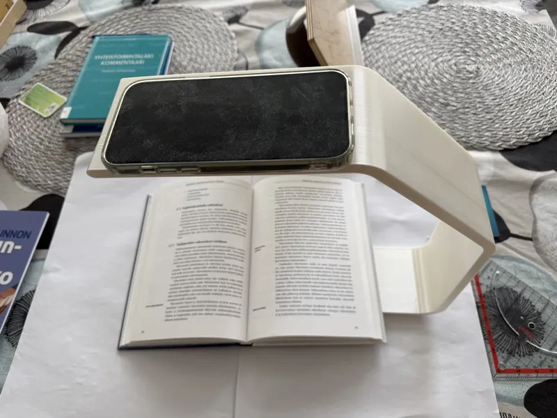 Physical scanning stand with iPhone mounted above an open book, showing the recommended setup for scanning.